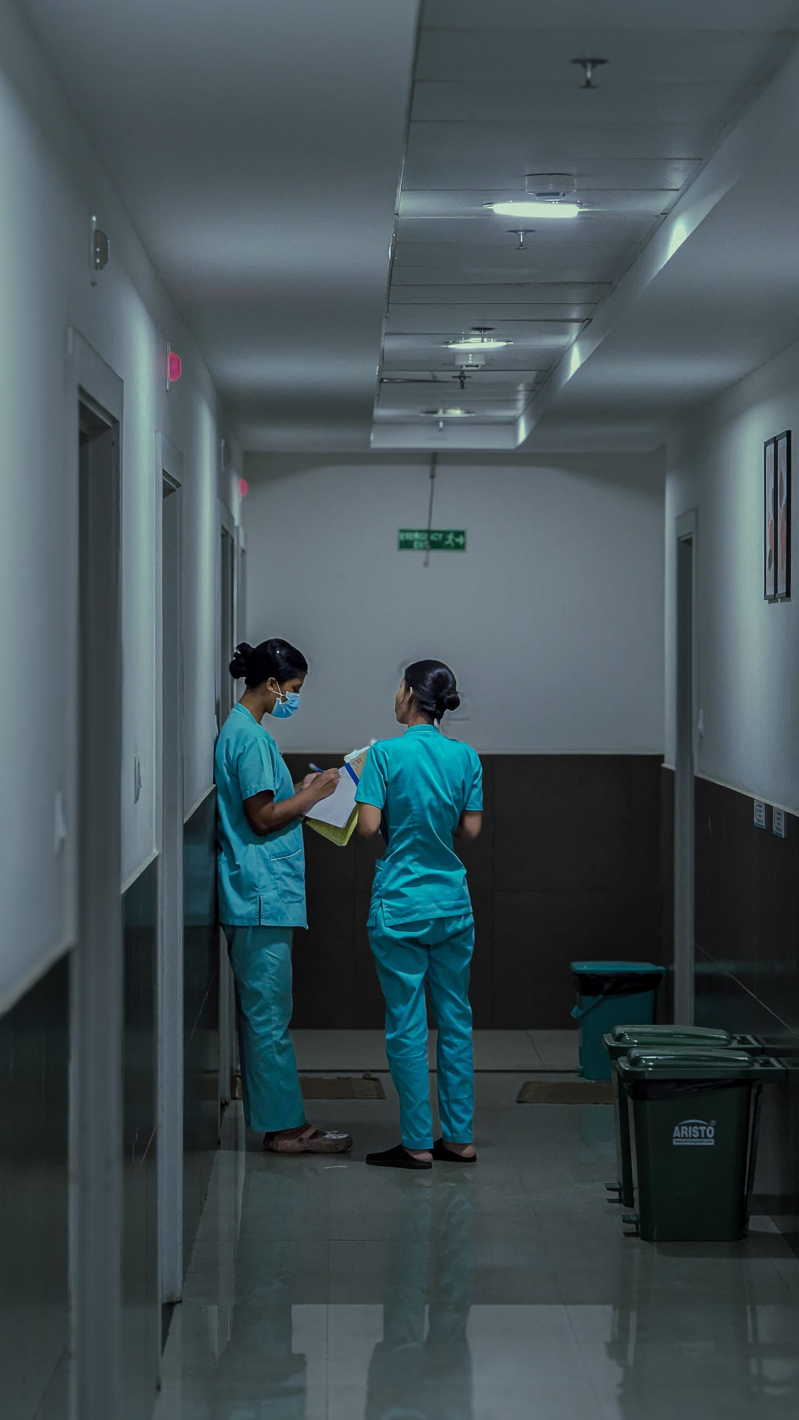 Nurses conferring over notes in a hospital corridor